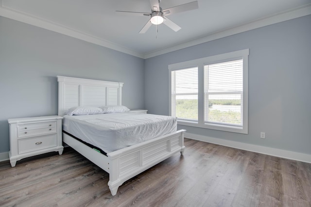 bedroom with baseboards, crown molding, and wood finished floors