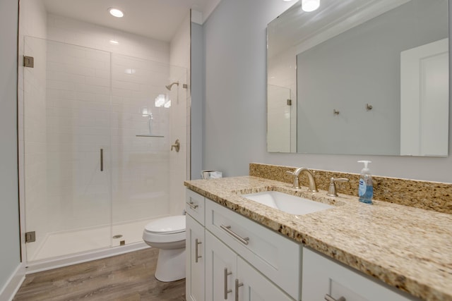 full bathroom featuring recessed lighting, toilet, a shower stall, vanity, and wood finished floors