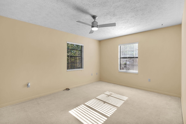 spare room featuring a textured ceiling, a ceiling fan, light colored carpet, and baseboards