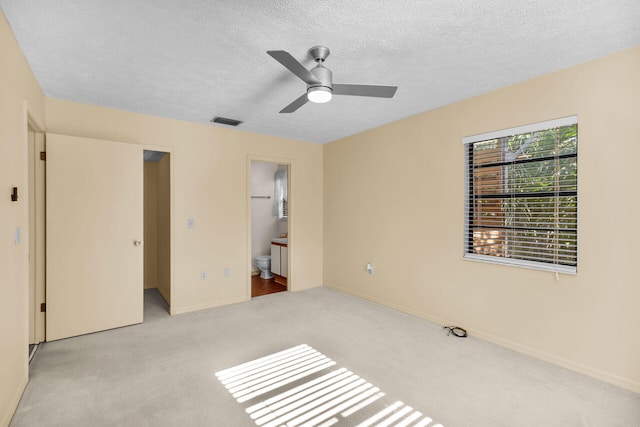 unfurnished bedroom with visible vents, light carpet, connected bathroom, a textured ceiling, and baseboards