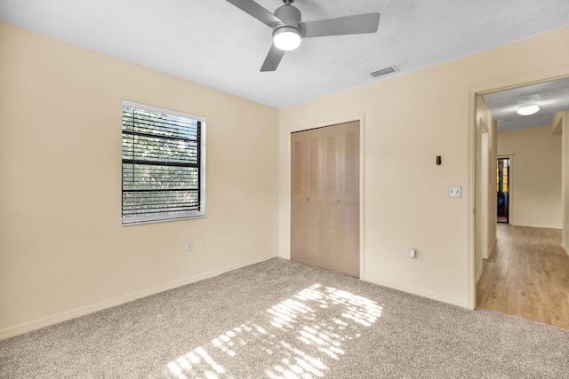 unfurnished bedroom with a textured ceiling, a closet, carpet flooring, and visible vents