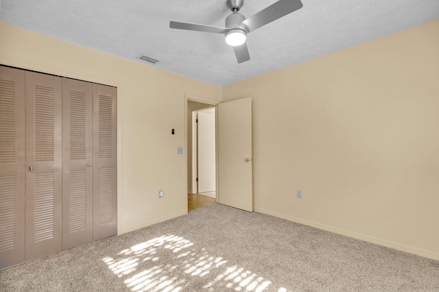 unfurnished bedroom featuring light carpet, a textured ceiling, visible vents, and a closet