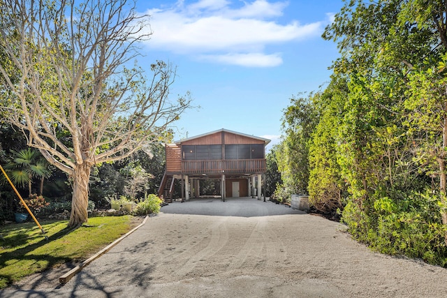 view of front facade with a carport, a sunroom, driveway, and stairway