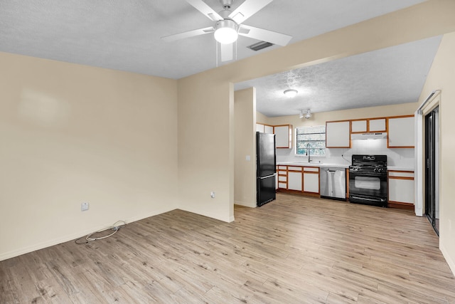 kitchen with light wood finished floors, light countertops, a sink, a textured ceiling, and black appliances