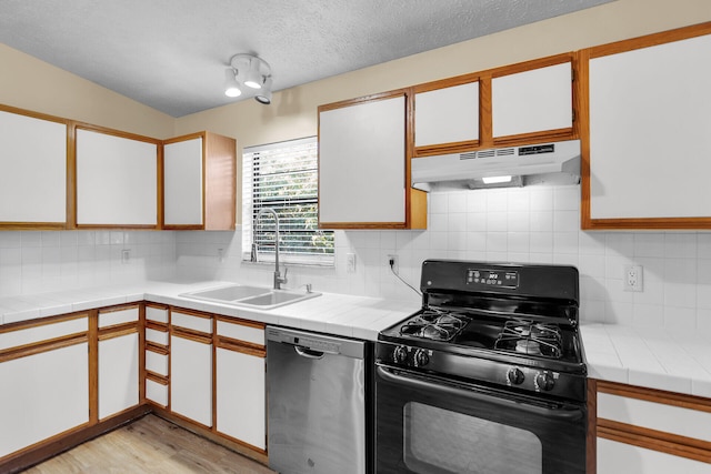 kitchen with black gas range, under cabinet range hood, a sink, white cabinets, and stainless steel dishwasher