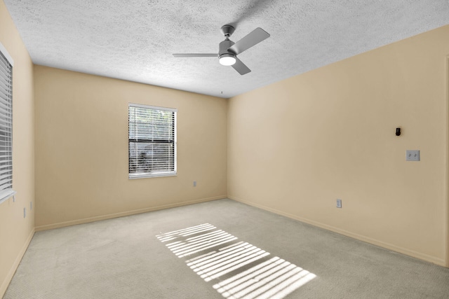 spare room featuring ceiling fan, baseboards, a textured ceiling, and light colored carpet
