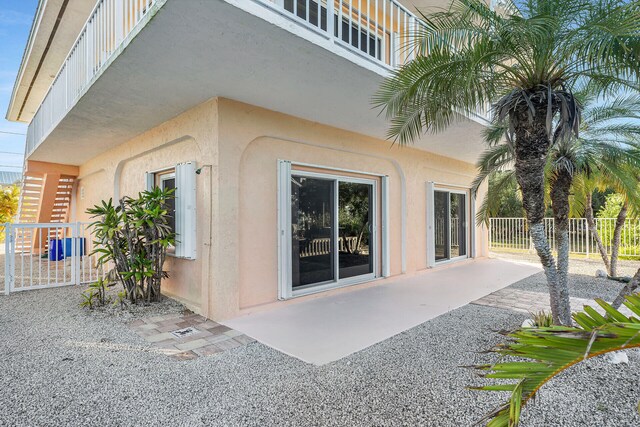 view of exterior entry with stucco siding, a patio, and fence