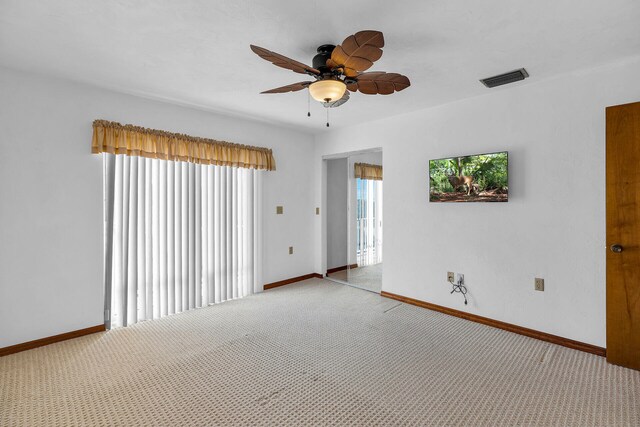 carpeted empty room featuring visible vents, a ceiling fan, and baseboards