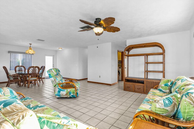 living room featuring light tile patterned floors, baseboards, washer / clothes dryer, and a ceiling fan