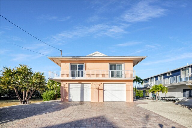 view of front facade featuring a balcony, stucco siding, decorative driveway, and a garage