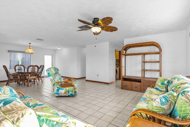 living area with light tile patterned floors, baseboards, washer / clothes dryer, and ceiling fan