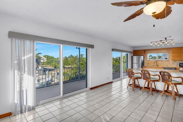 dining area featuring light tile patterned flooring, baseboards, and ceiling fan