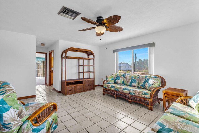 living room with light tile patterned floors, visible vents, baseboards, and ceiling fan