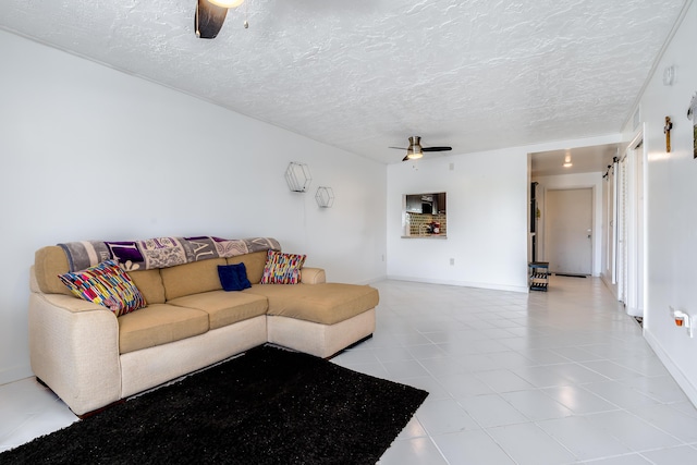 living area featuring a textured ceiling, light tile patterned floors, and a ceiling fan