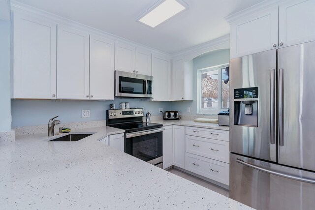 kitchen with appliances with stainless steel finishes, white cabinets, and a sink