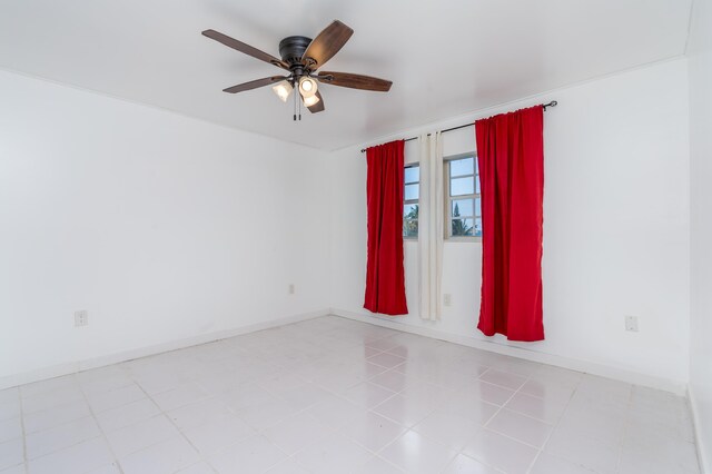 unfurnished room featuring a ceiling fan and baseboards