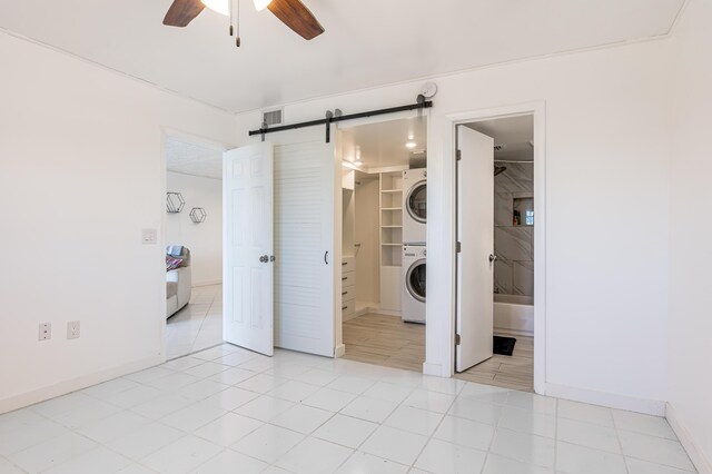 unfurnished bedroom with a barn door, visible vents, stacked washer / drying machine, ensuite bathroom, and a walk in closet