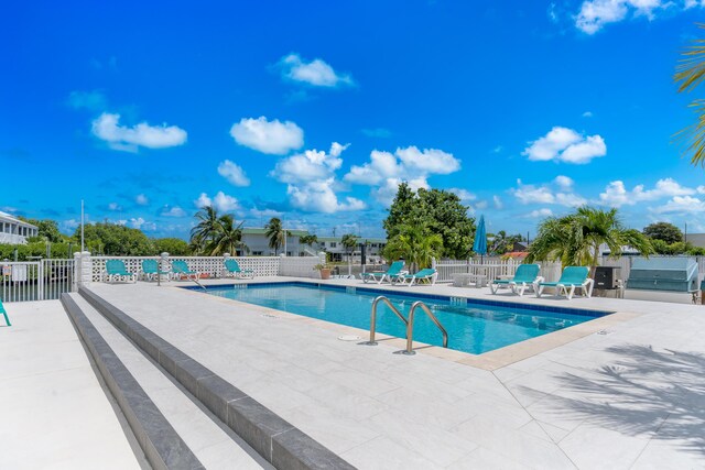 pool featuring a patio, grilling area, and fence