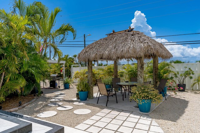 view of patio with fence, outdoor dining area, and a gazebo