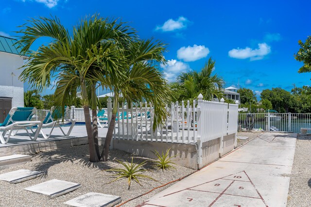 view of property's community with shuffleboard, a water view, and fence