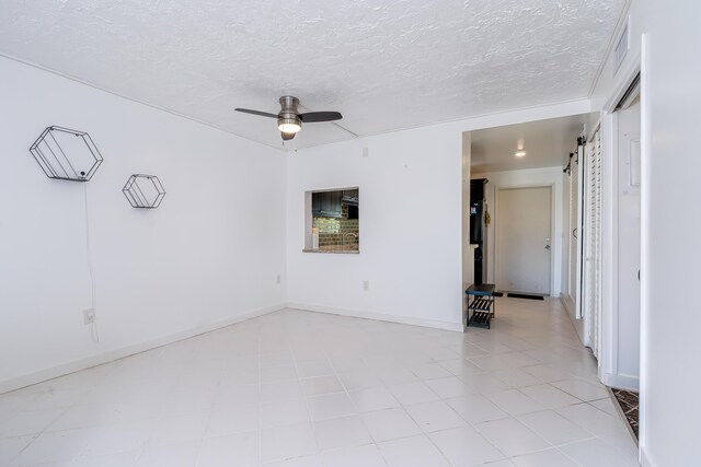 unfurnished room featuring a ceiling fan, visible vents, a textured ceiling, and a barn door