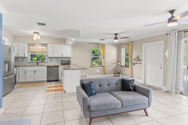 living room featuring light tile patterned floors, baseboards, visible vents, a ceiling fan, and crown molding