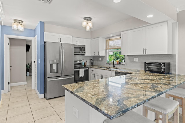 kitchen featuring stainless steel appliances, a peninsula, a sink, and white cabinetry