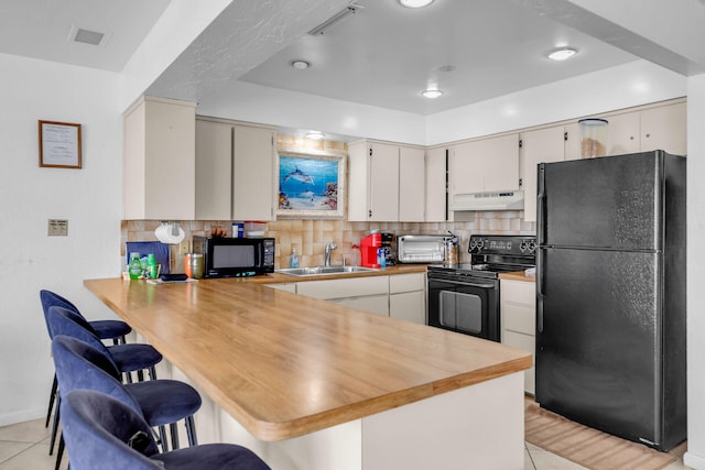 501 9th St, Key Colony, FL 33051 - kitchen featuring black appliances, under cabinet range hood, a sink, a peninsula, and light tile patterned floors