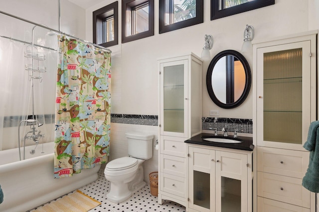 full bathroom featuring shower / tub combo, wainscoting, toilet, vanity, and tile walls