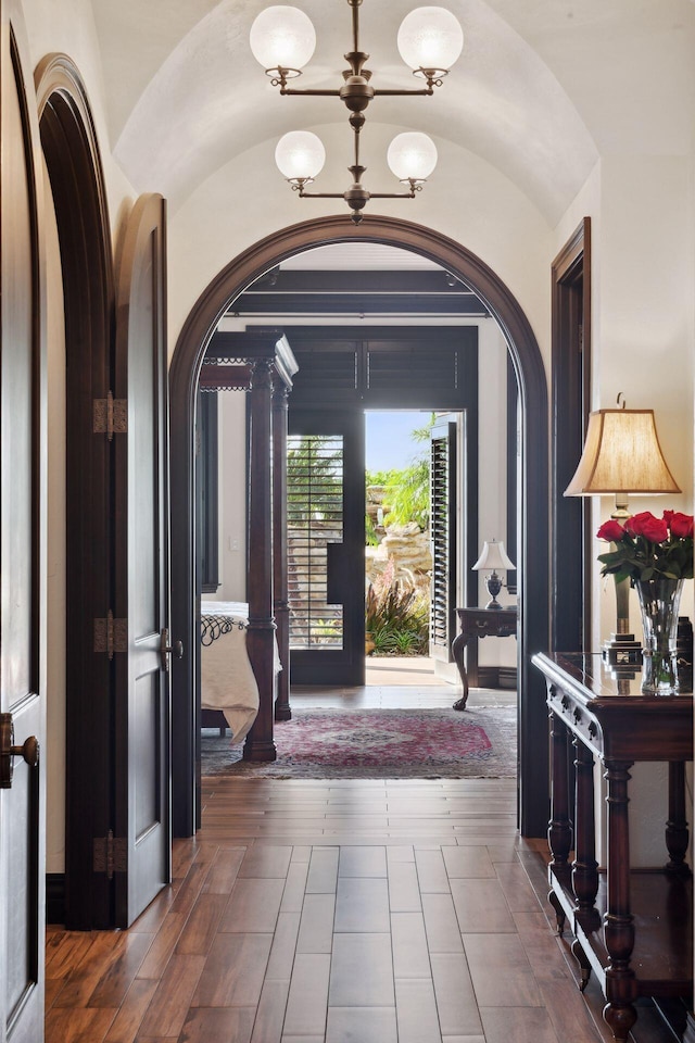 foyer featuring vaulted ceiling, arched walkways, and an inviting chandelier