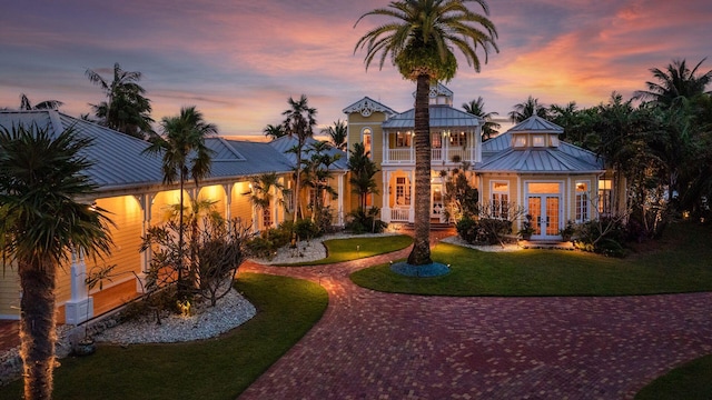 exterior space featuring a balcony, metal roof, a standing seam roof, decorative driveway, and french doors