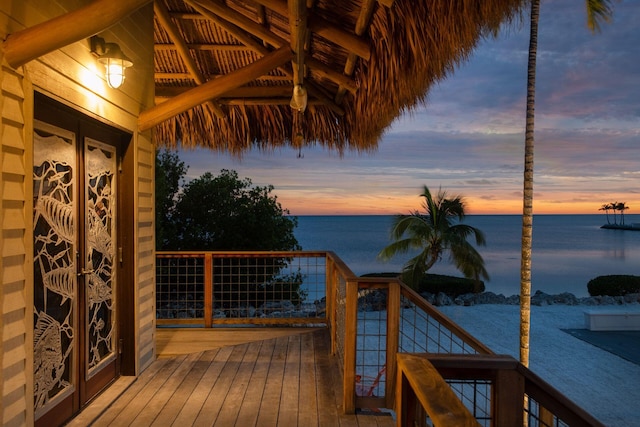 deck at dusk with french doors and a water view