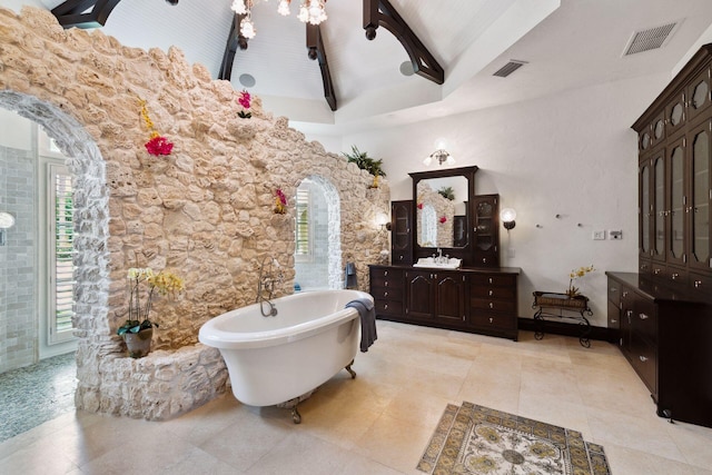 full bath featuring a freestanding bath, vanity, visible vents, and vaulted ceiling with beams