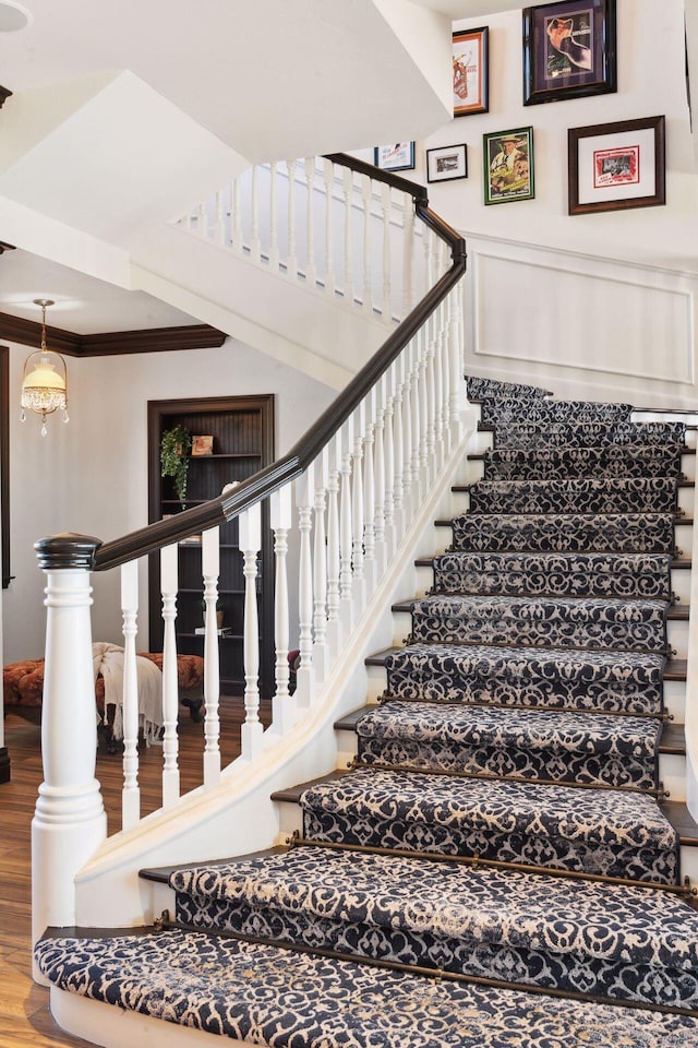 stairs with ornamental molding and wood finished floors