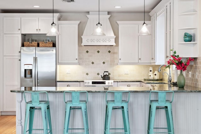 kitchen featuring a kitchen breakfast bar, pendant lighting, dark stone countertops, and white cabinets