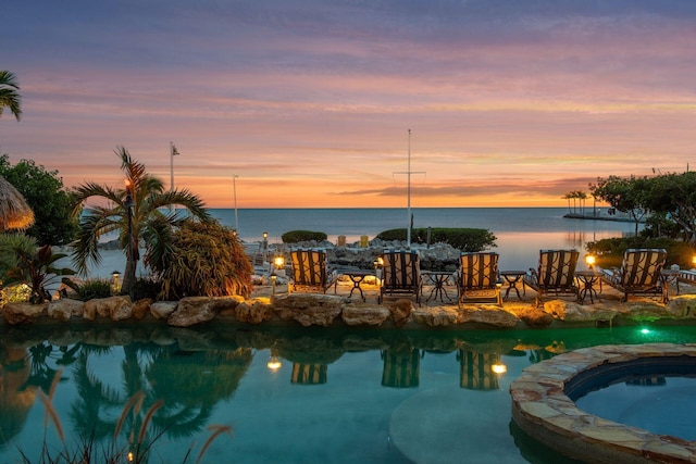 exterior space with a pool with connected hot tub and a water view