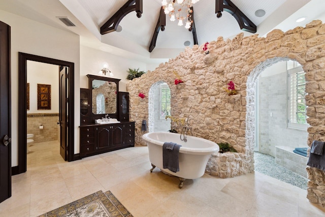 full bath featuring visible vents, toilet, a wainscoted wall, a soaking tub, and beamed ceiling