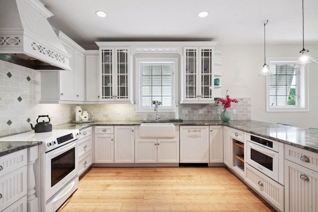 kitchen featuring glass insert cabinets, electric stove, white cabinets, and custom exhaust hood