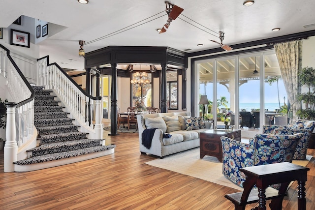 living room with visible vents, stairway, wood finished floors, an inviting chandelier, and ornate columns