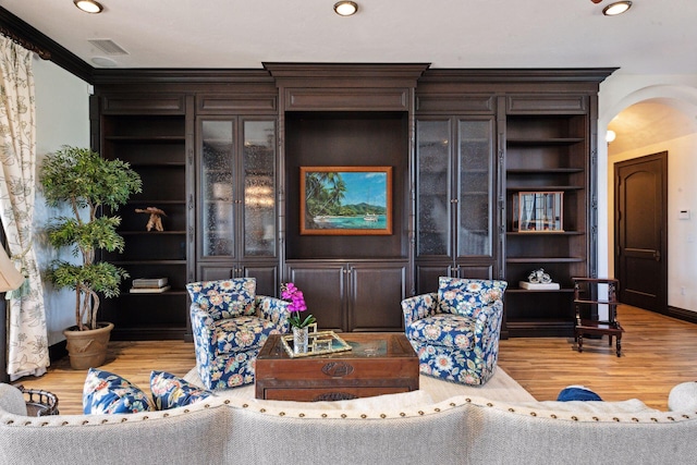 living room with built in features, arched walkways, and wood finished floors