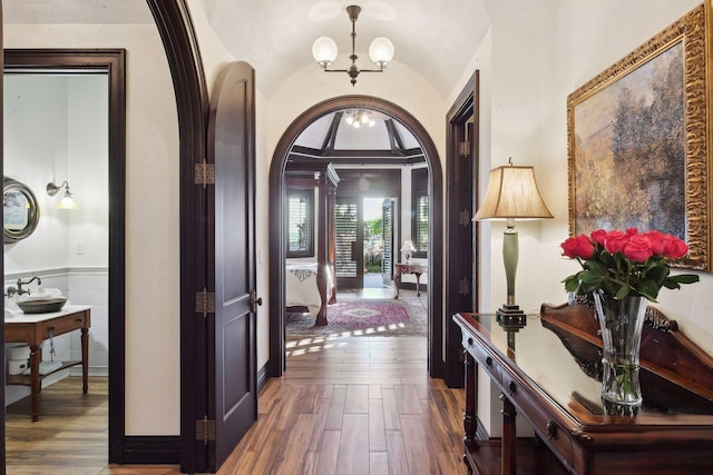 entrance foyer with arched walkways, dark wood-style flooring, lofted ceiling, and an inviting chandelier