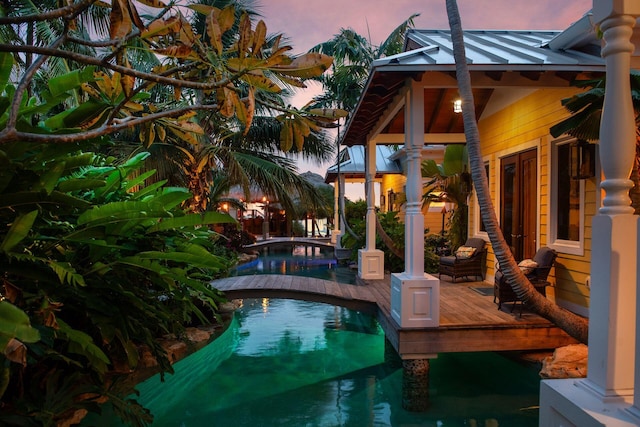 pool at dusk with an outdoor pool and a deck