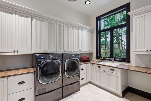 laundry area with washer and clothes dryer, light tile patterned floors, cabinet space, a sink, and baseboards