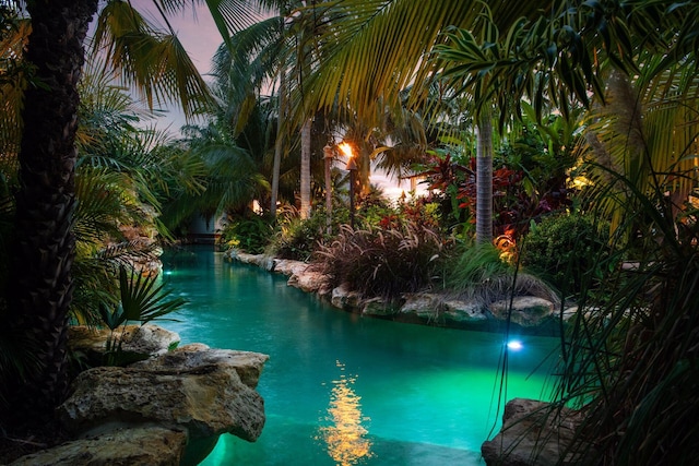 pool at dusk featuring a water view