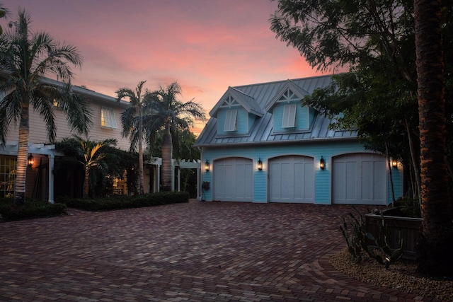 view of front facade with metal roof, decorative driveway, a standing seam roof, and an attached garage