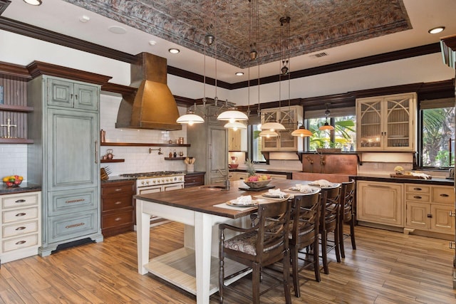 kitchen featuring pendant lighting, island exhaust hood, open shelves, cream cabinets, and glass insert cabinets