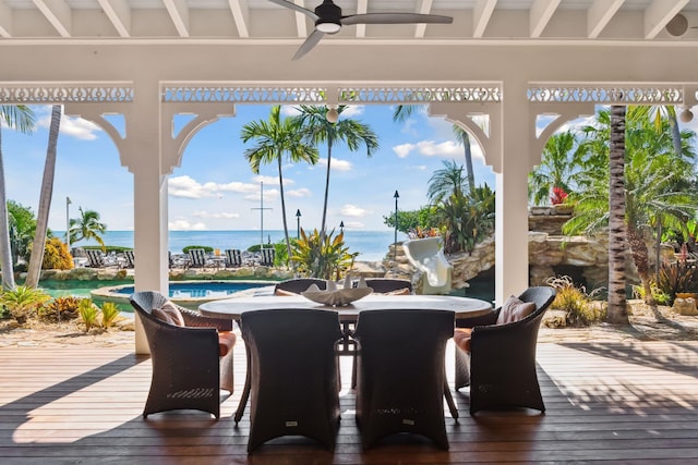 deck with a water view, ceiling fan, an outdoor pool, and outdoor dining space