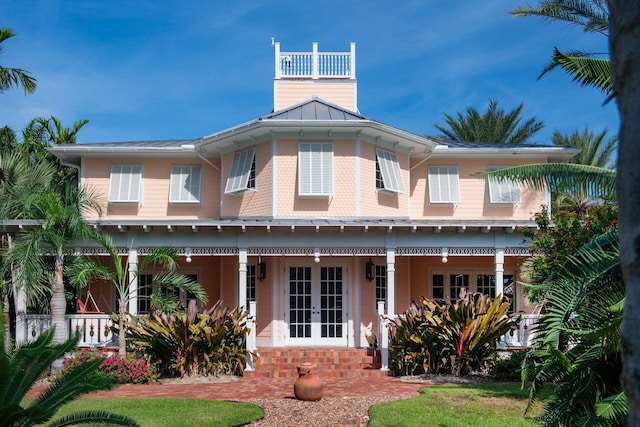 view of front facade with a standing seam roof, brick siding, metal roof, and french doors