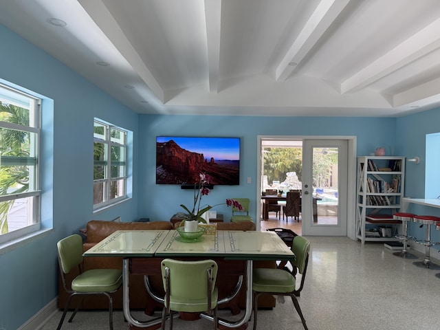 dining area featuring speckled floor, beam ceiling, and french doors