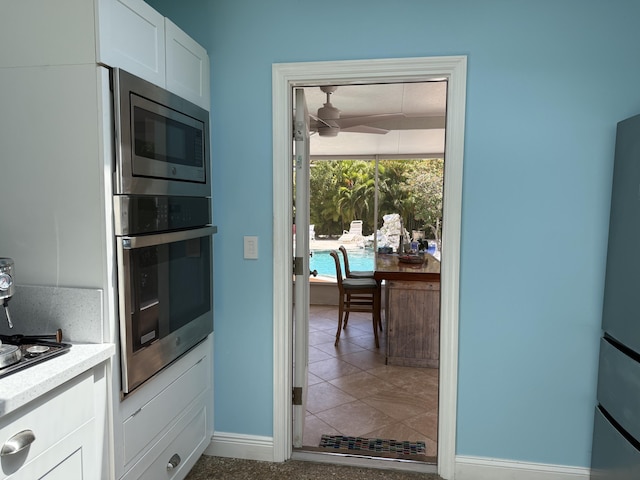 kitchen with baseboards, ceiling fan, light countertops, white cabinets, and appliances with stainless steel finishes